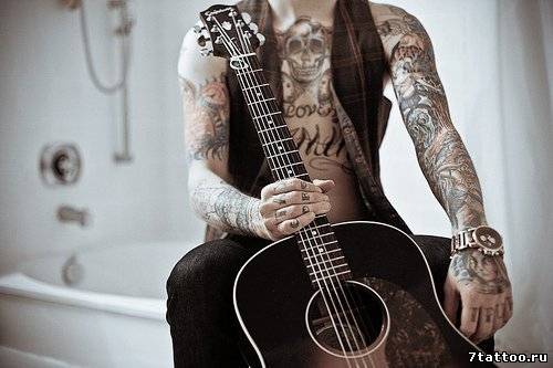 Парень с гитарой с татуировками по всему телу