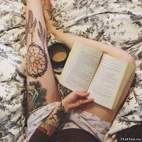 Читающая книгу с татуировками на ногах