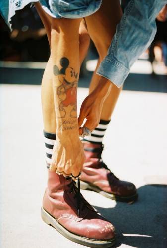 Микки Маус на руке девушки завязывающей ботинки