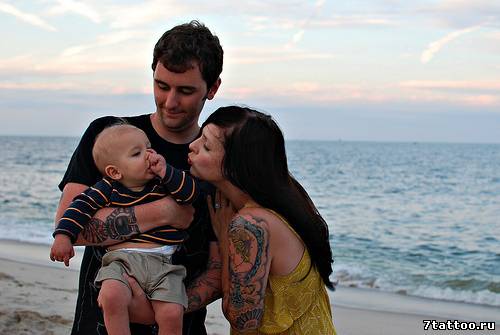 Семья с ребенком у моря и тату на руке мамы