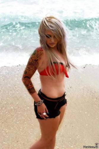 Девушка у моря с татуировкой на руке