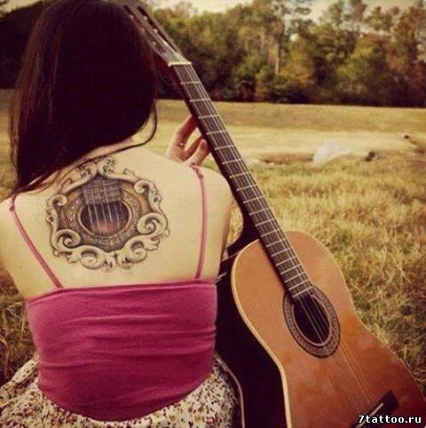 Фрагмент грифа любимой гитары на спине девушки