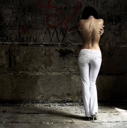 Узор на спине девушки в белых брюках