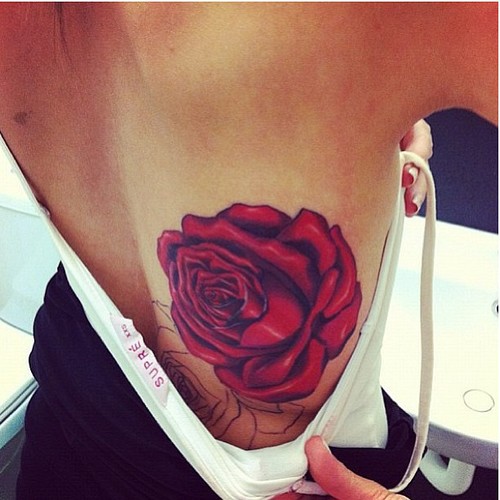Красная роза в нижней части спины девушки